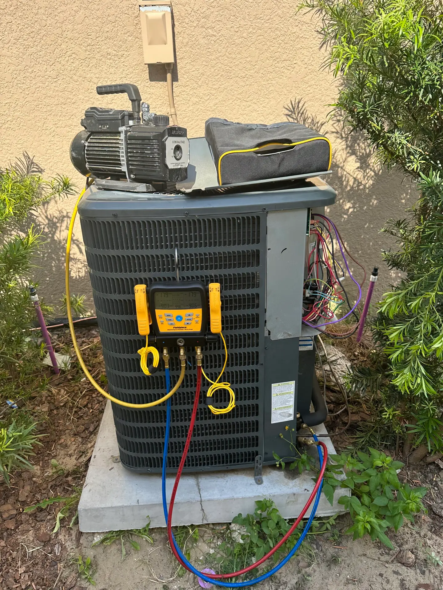 Indoor Climate Experts technician checking refrigerant with gauges during AC maintenance in Winter Haven, FL